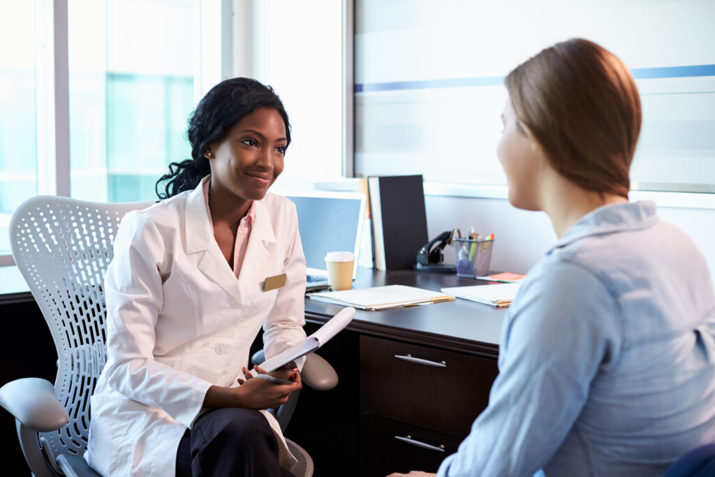 about us- Doctor In Consultation With Female Patient In Office